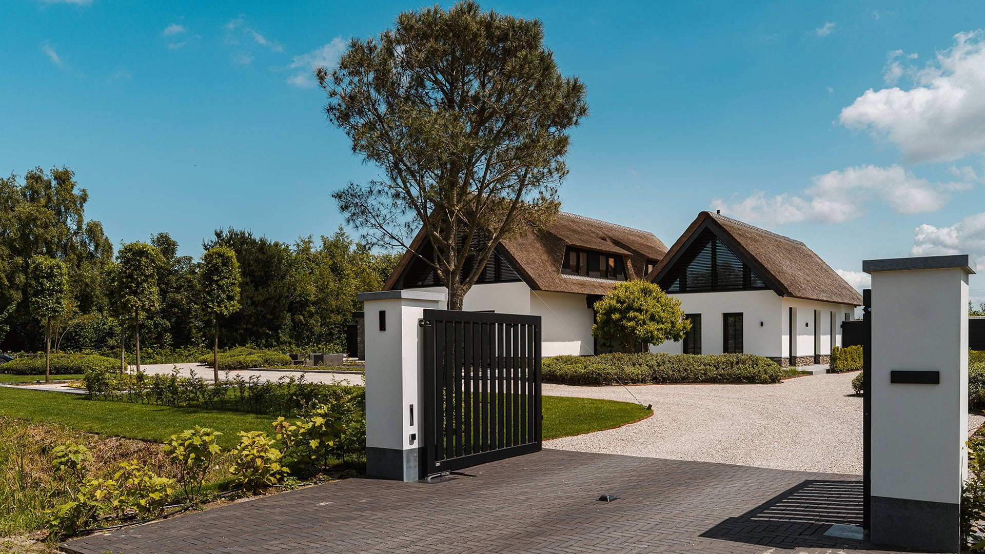 Oprit met open poort van villa met kantelbare lamellen